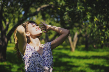 Naklejka premium Young attractive woman adjusting her hair in the garden