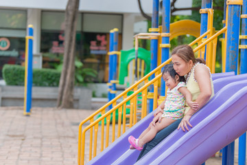 Fototapeta na wymiar Beautiful young mother play with your daughter with fun at playground,Happy mother day,Thailand people