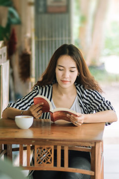 Young pretty business woman reading book and enjoy coffee in coffee shop in free time