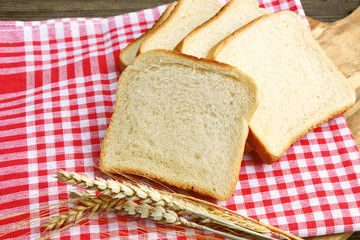 White bread toast with Wheat and red tablecloth on wooden background.