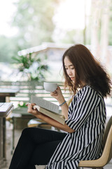 Fototapeta premium Young pretty business woman reading book and enjoy coffee in coffee shop in free time