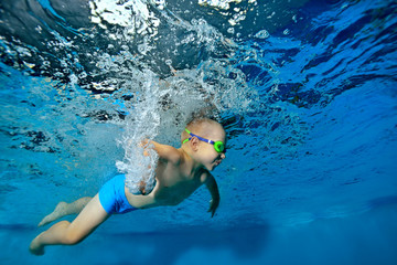 Happy little boy learning to swim underwater in the pool on blue background. Portrait. Horizontal orientation