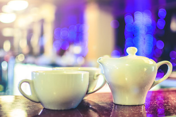 kettle and two cups for tea on the table on a background of blurry bokeh