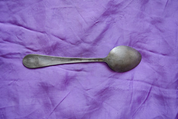 Silver set against the violet background. Silver spoon and fork with an ancient texture. Antique...