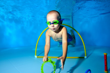 A little boy goes in for sports in the pool and dives underwater to the bottom for toys. Portrait....