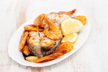 boiled fish with shrimps and lemon on white dish