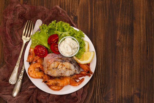 boiled fish with shrimps and salad on white dish