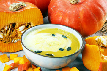 Roasted pumpkin and carrot soup with cream and pumpkin seeds on table.