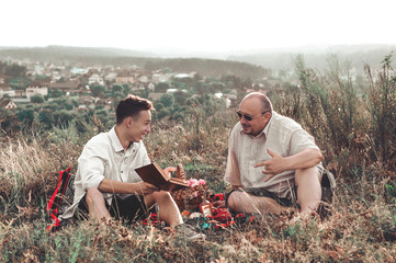 happy father and son having a rest on nature on a summer day