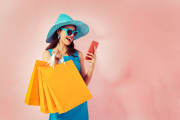 Happy Asian woman using cell phone on pink background,colorful shopping concept.