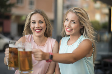 Blonde sister woman drinking beer in bar, blonde with blonde.looking at camera.