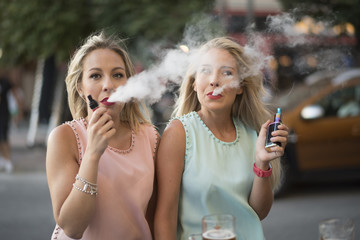 two blond sisters smoking from vaporizer pipe