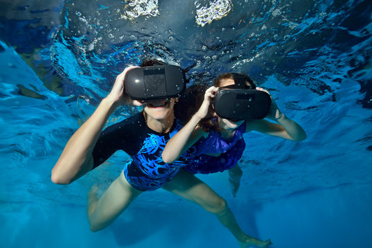 Happy family, mom and baby play in virtual reality helmets underwater in the pool. Close up. Shooting underwater. The horizontal orientation of the image