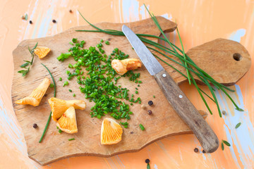 Pfifferlinge und Schnittlauch auf einem Schneidebrett