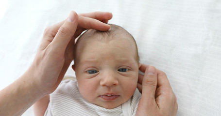 Mother stroking the child to feel the fontanel of 1 months baby girl