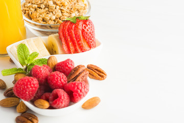 Healthy breakfast with fresh berries, nuts, bananas on white background