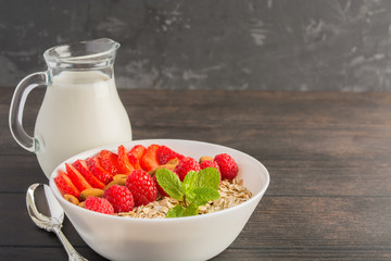 Healthy breakfast concept with oatmeal, strawberries, raspberries, almonds and milk