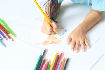 A girl drawing with color pencil on white paper.