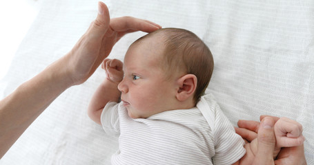 Mother stroking the child to feel the fontanel of 1 months baby girl