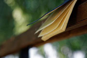 Wind turns the pages of open Notebook lies on wooden handrail in park, business concept
