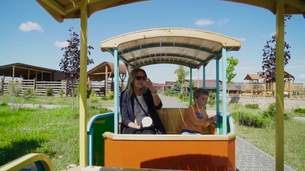 Beautiful woman and little boy ride open car at the contact zoo