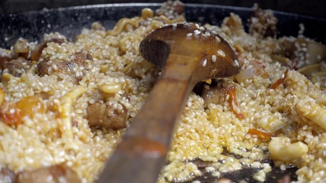 Cooking Spanish paella, a famous typical spanish rice dish. Adding and stiring until the rice starts being a bit cooked, Zoom and close upview.