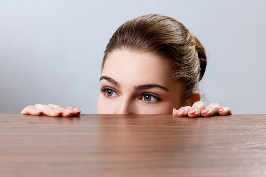Woman peeping under the edge of wooden table