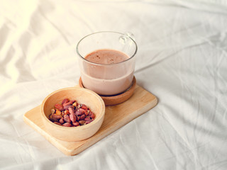 Small snacks set of salted beans and hot chocolate served on the bed.