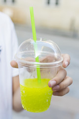 hand with glass of soda or iced fruit on the outdoor street