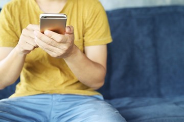 Young male casual wear using on cell phone during rest on sofa. sitting in watching message on mobile phone during break relax.