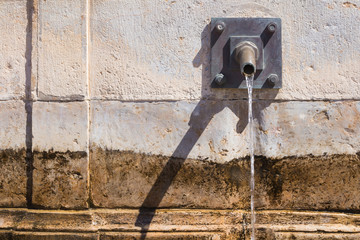 Stone wall outdoors with a water-tap