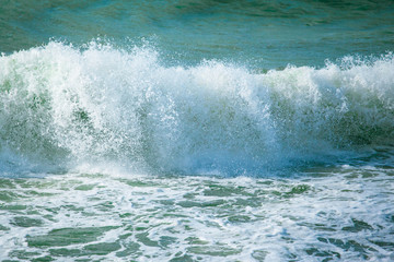surface of turquoise ocean water with waves, spray and white foam