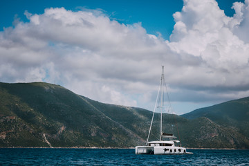 Catamaran ship in open sea near Fiskardo. Big clouds moving over the mountain shape of Ithaki island. Kefalonia Island Greece