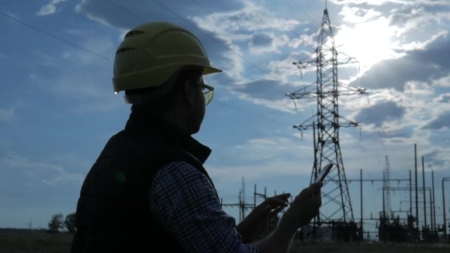 silhouette of engineer electricity talking and use phone during sunset