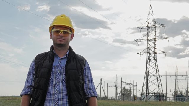 Engineer electricity looks at the camera during sunset.