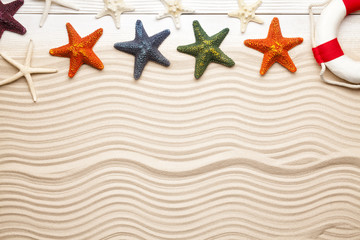 Fototapeta na wymiar Summer background - top view of starfish and lifebuoy on beach sand