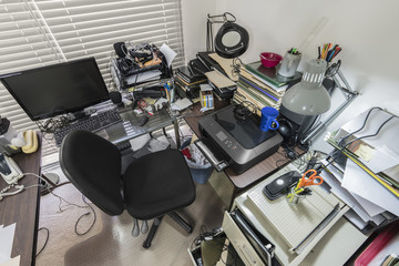 Messy office desk with stacks of files and disorganized clutter. - Powered by Adobe