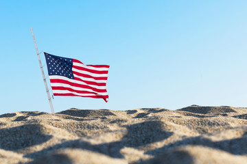 American flag in the sand against a blue sky. . Concept