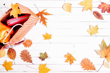 Autumn composition. Paper bag with autumn yellow dried leaves on wooden whute background. Flat lay, top view, copy space 