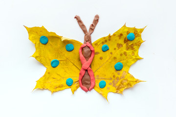 Fall Leaf Crafts for Kids. Craft handmade butterfly from dry yellow leaves and red, brown and blue plasticine, modeling clay. Ideas for kids arts and crafts isolated on white