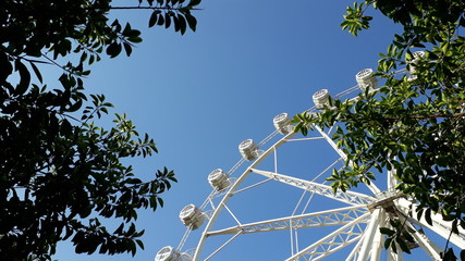 Modern ferris wheel at a fair in summer, with day blue sky background.