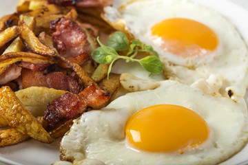 Homemade eggs with French fries and fried bacon on plate