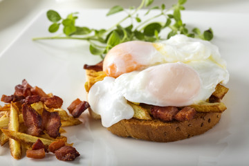Toast sandwich with two poached eggs, French fries and bacon