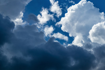 Texture of white and gray storm clouds on a blue sky in the sunlight, background