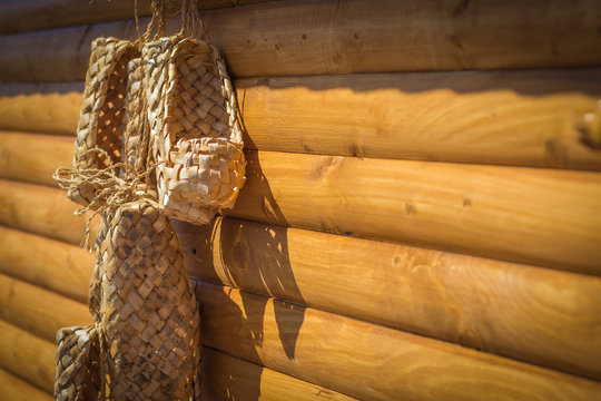 Birchen woven bast shoes hang on a log wall, selective focus