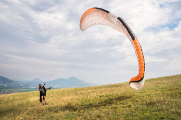 The paraglider opens his parachute before taking off from the mountain in the North Caucasus. Filling the parachute wing with air before takeoff