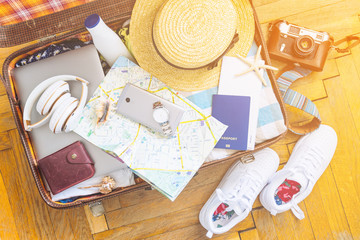 woman staff in suitcase. travel concept. camera laptop wallet hat on floor. overhead view