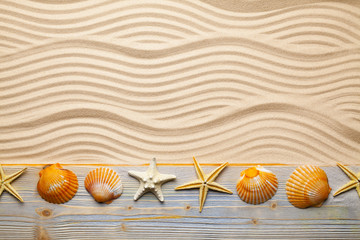 Fototapeta na wymiar Summer beach - shells and starfish on wooden plank and beach sand