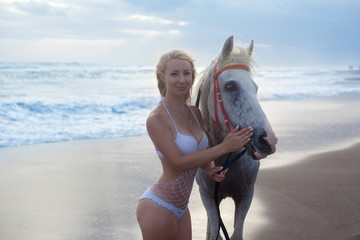 Sexy young woman walking with horse at the beach, horseback