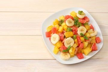 Bowl of healthy citrus fruit salad on light wooden background. Top view.